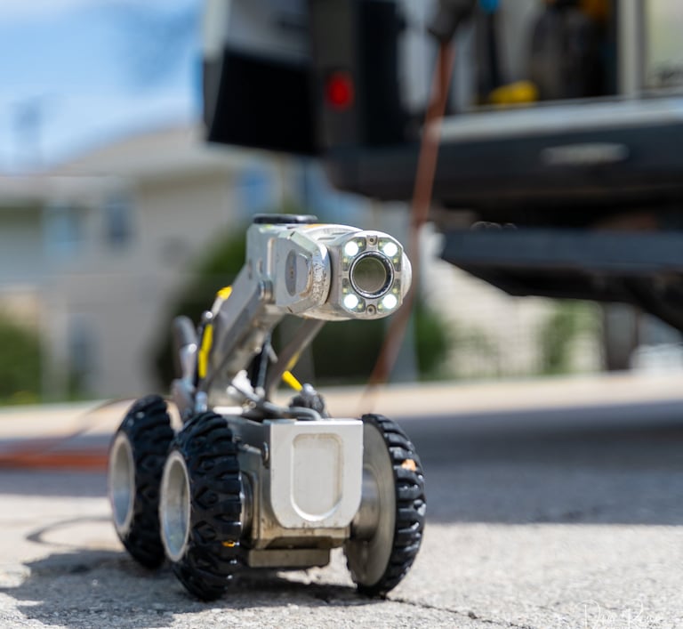 Sewer pipe inspection robot equipped with camera and lights, used to assess underground infrastructure.