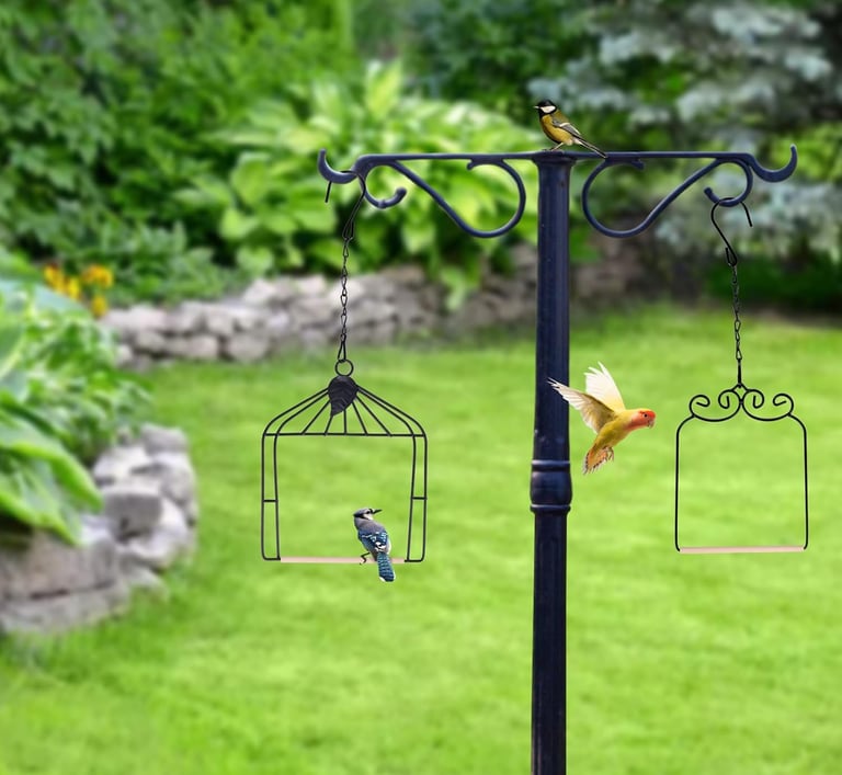 A black metal bird feeder pole in a green garden with a blue jay and yellow birds.