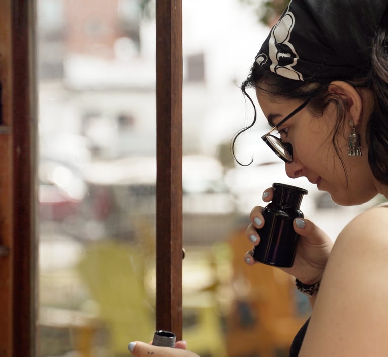 A woman wearing glasses smells different floral and earthy herbs and spices in an apothecary bottle