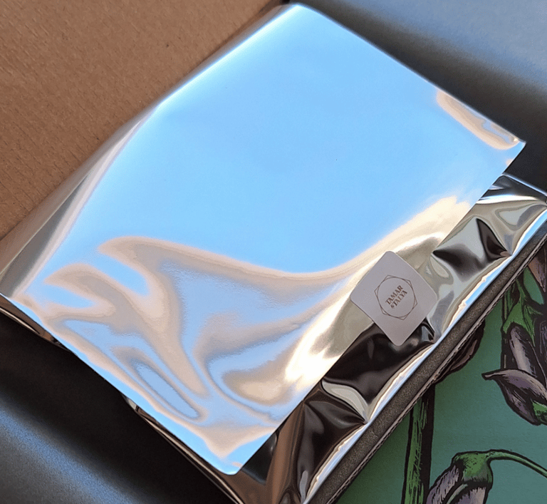 Shiny silver foil package with a Tamar & Talya brand sticker inside a shipping box.