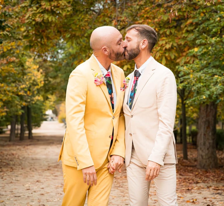 "Pareja gay casada en Madrid, besándose en un parque, celebrando su boda y el amor."