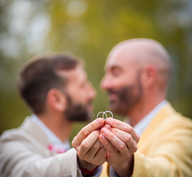 "Pareja gay casada mostrando sus anillos de boda en Madrid, celebrando su amor y unión."