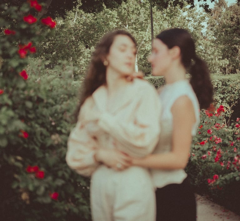 "Pareja lesbiana en el jardín con rosas, foto romántica y desenfocada celebrando su amor en una boda gay."