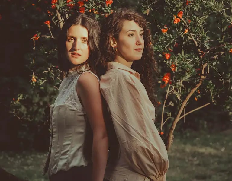 Dos mujeres lesbianas en un jardín primaveral al atardecer, simbolizando el amor LGBTQ+. Bodas gay en Madrid.