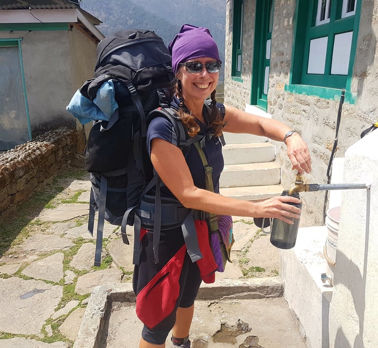 Karen Felton, filling a water bottle while trekking in the Nepal Himalaya