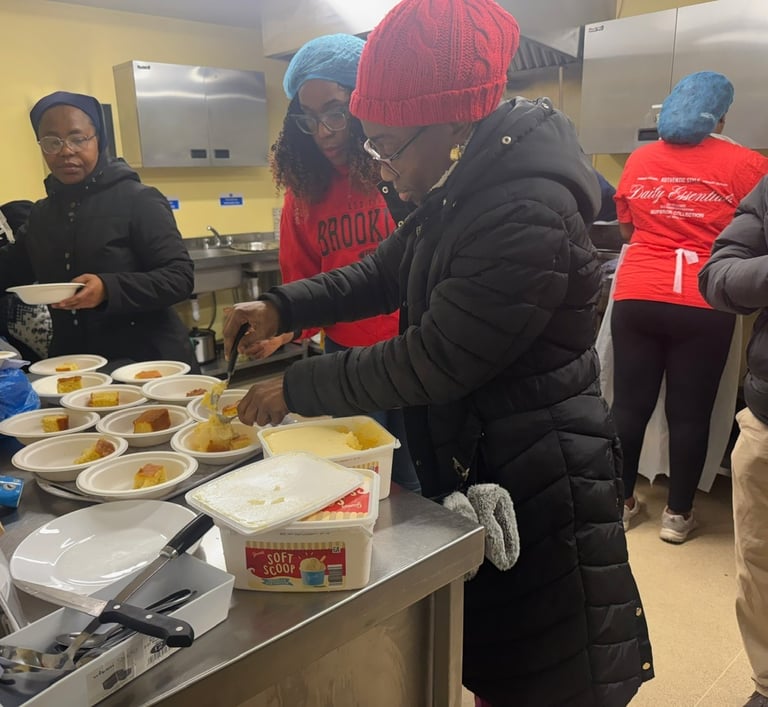 Volunteers in a soup kitchen serving hot meals and desserts to community members in need.
