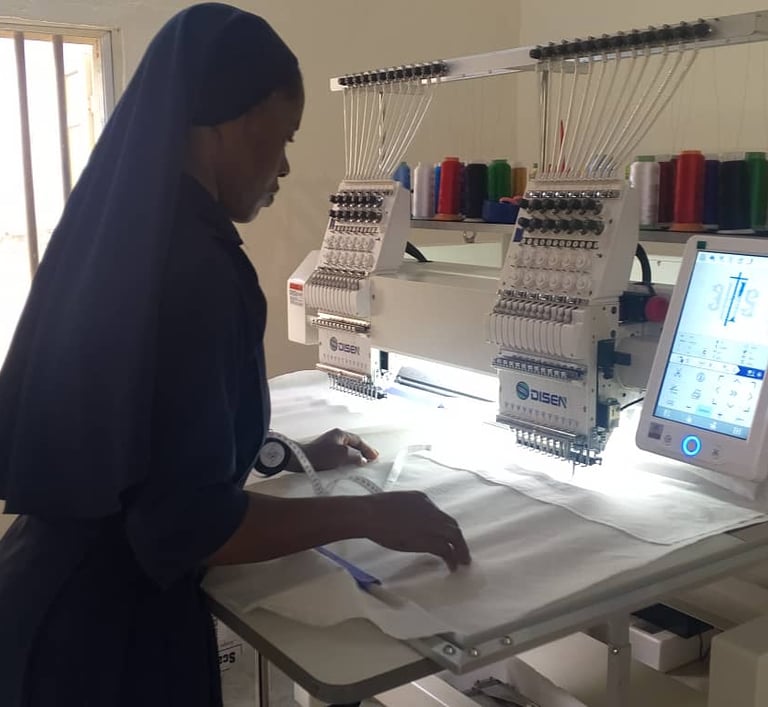 A nun uses a multi-head industrial embroidery machine to sew patterns on white fabric in a workshop.