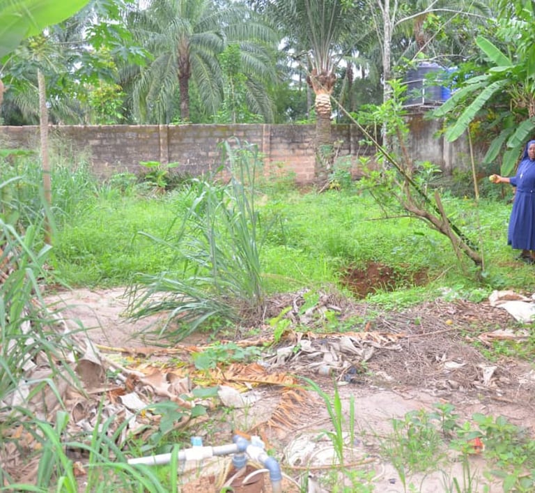 A Catholic nun standing in a lush tropical garden with banana trees and palm plants.