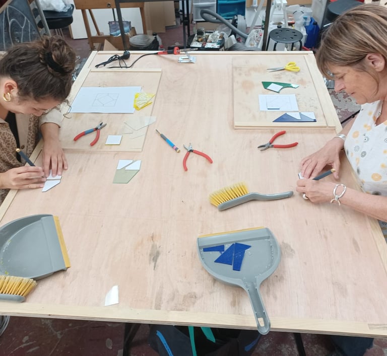 Cours de vitrail : table de travail, outils de découpe et verre à l'atelier.