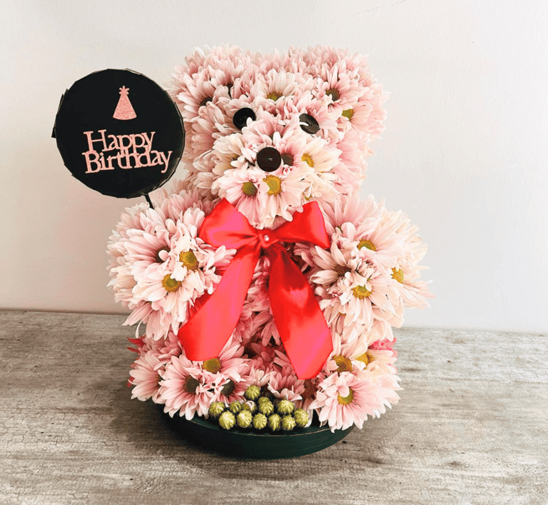 Oso de feliz cumpleaños elaborado con flores. Margaritas rosas