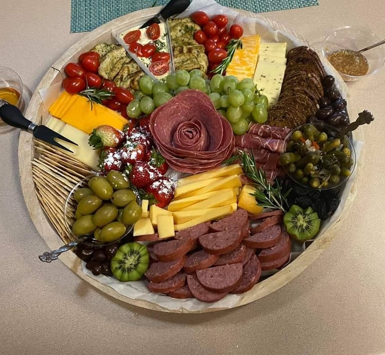 Gourmet charcuterie board with a salami rose, assorted cheeses, crackers, grapes, and olives.