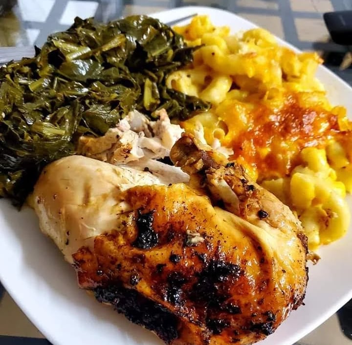 Baked chicken dinner served with creamy macaroni and cheese and slow-cooked collard greens.