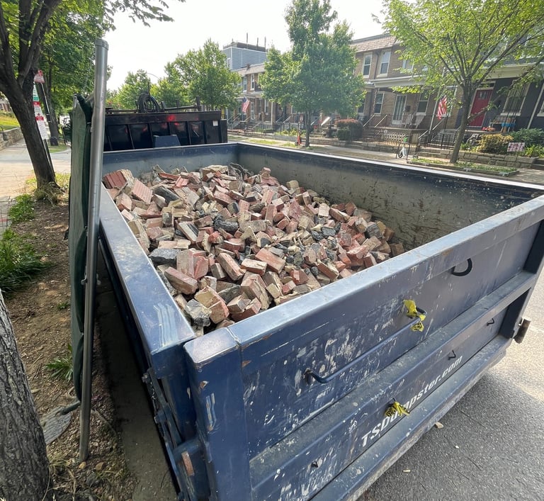 a blue dumpster truck with bricks in the back