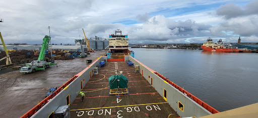 Panoramic view of a cargo ship docked at port with cranes and equipment on deck