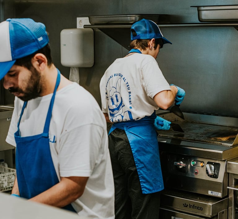 Cocineros de Flipa trabajando en cocina con uniforme azul y plancha caliente