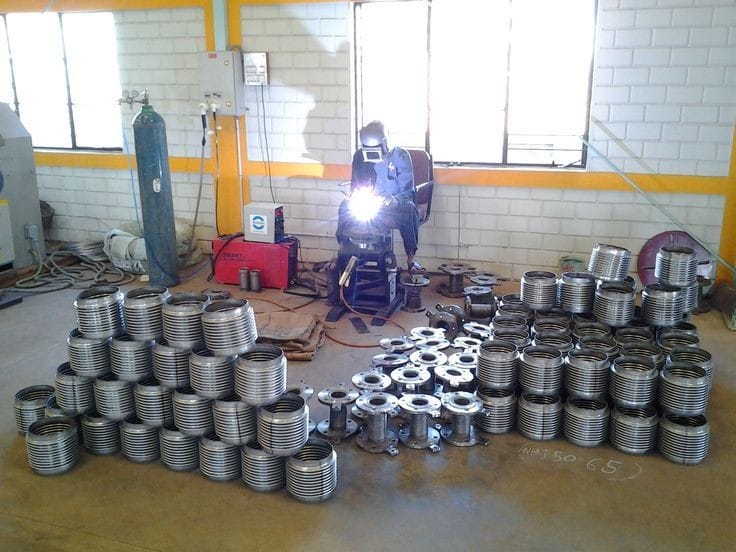 a man welding a metal pipe in a warehouse