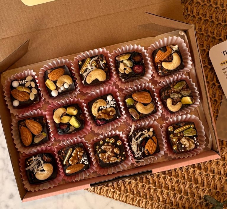 A box of panjeeri bites, chocolate and nuts on top