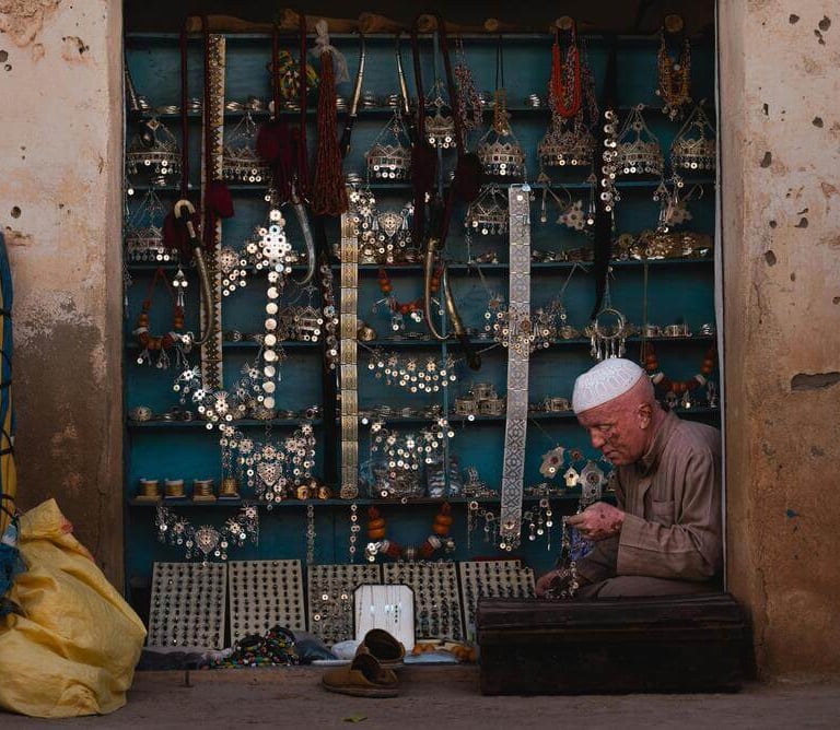 Moroccan artisan working in a traditional shop with handmade jewelry and crafts