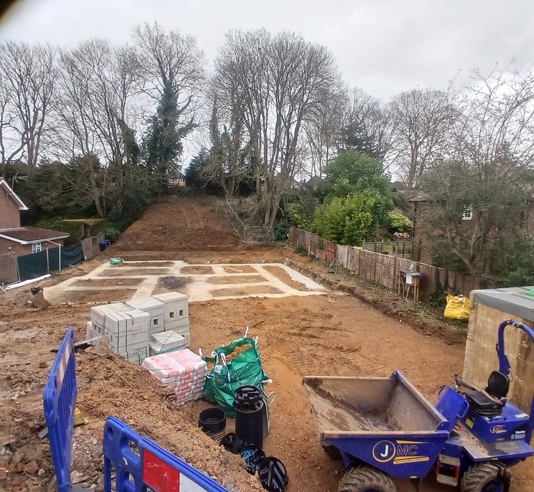 Concrete foundations for a new home construction project with a blue dumper truck and building supplies.