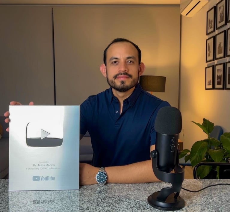 Content creator Dr. Jesús Macías holding a Silver YouTube Creator Award for 100k subscribers in a studio.