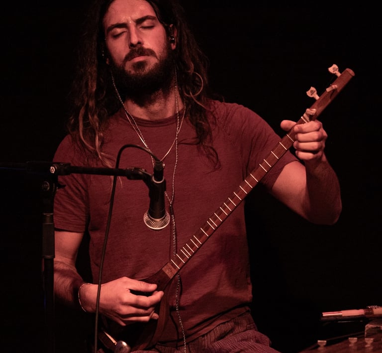 a man with long hair and a Persian Setar
