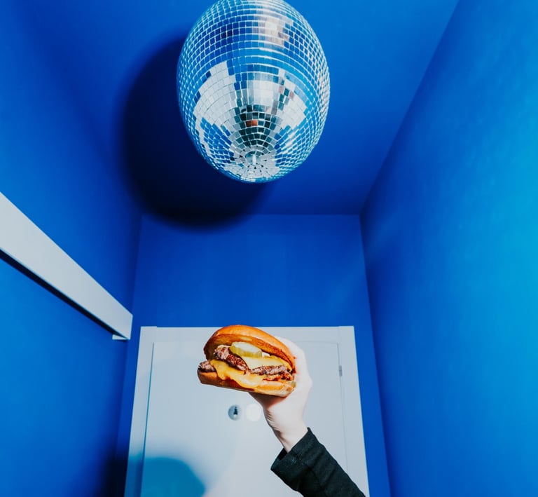 Burger de Flipa sostinguda sota una bola de discoteca en un espai blau, estil original i atrevit