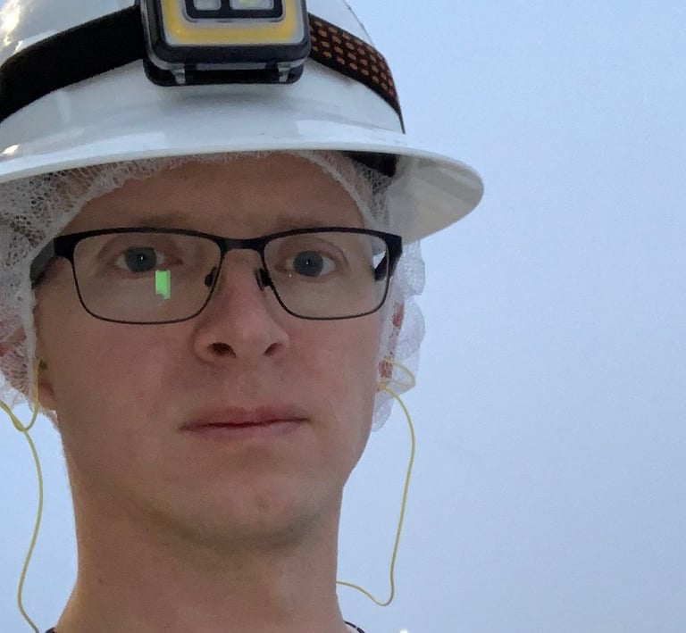 Tomkins dressed in a safety vest and hard hat standing outside on a snowy day.