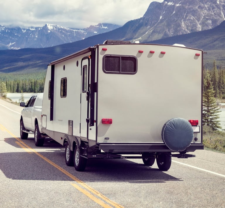 RV driving down road with mountains and trees.