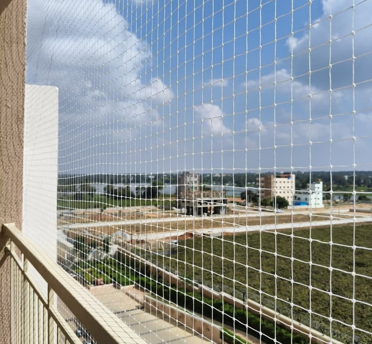 Technician from Sukumari Safety Nets carefully fitting a net on a high-rise balcony.