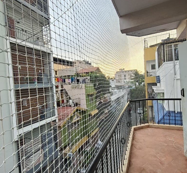 Evening view of a balcony protected by a safety net, with city lights twinkling in the background.