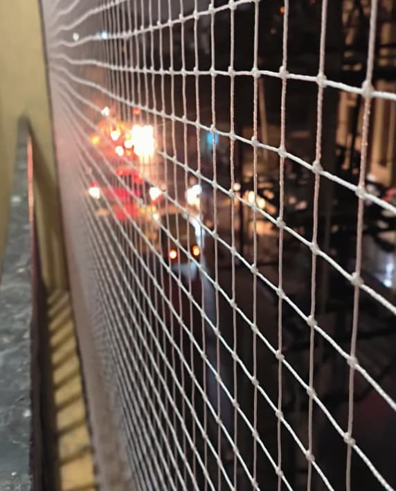 Close-up of a installed balcony safety net tightly secured on a high-rise apartment in Bengaluru.