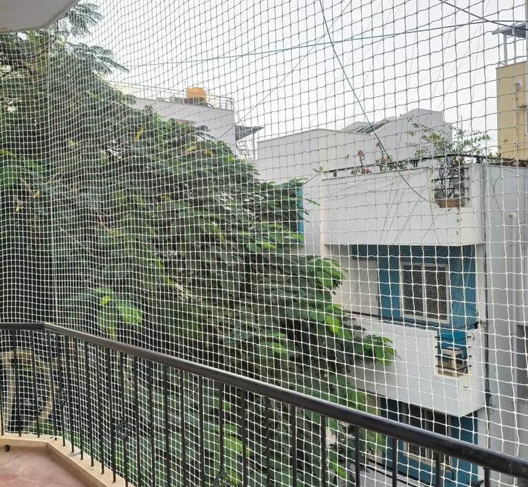 Close-up of sturdy pigeon netting installed seamlessly over a window in a Bengaluru home.