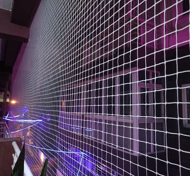 A child playing safely behind a tightly woven safety net on a high-rise window.