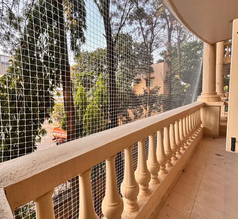 Wide shot showing a balcony fully covered with a durable safety net against a clear sky.