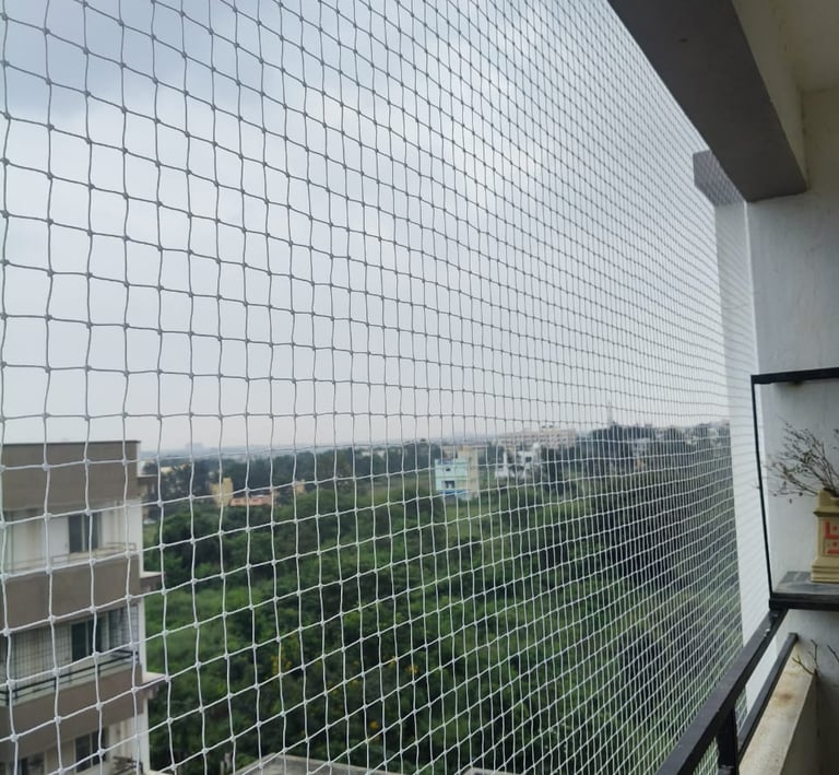 Wide shot showing a balcony fully enclosed with sturdy safety netting on a sunny day.