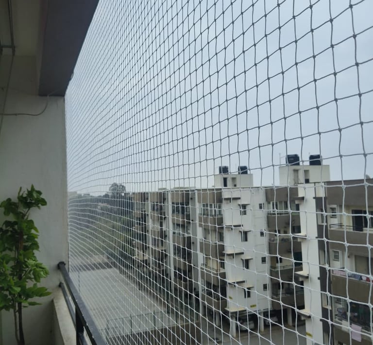 Technician carefully measuring and fitting a safety net on a balcony railing.