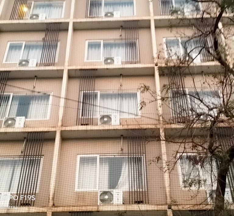Wide shot showing a high-rise balcony fully covered with a sturdy safety net in a residential area.
