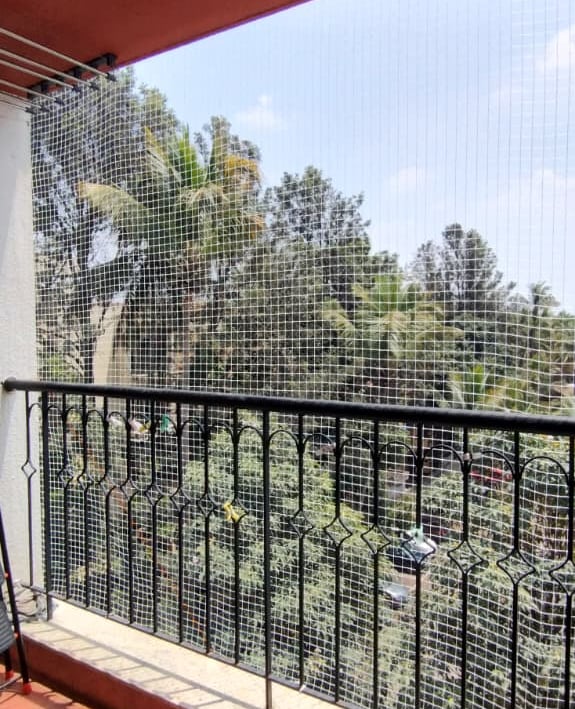 Technician carefully fitting a pigeon net frame on a window in a residential building.