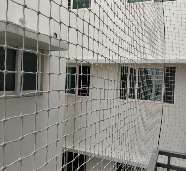 Daylight view of multiple apartment balconies secured with neatly installed safety nets by Arjilli E