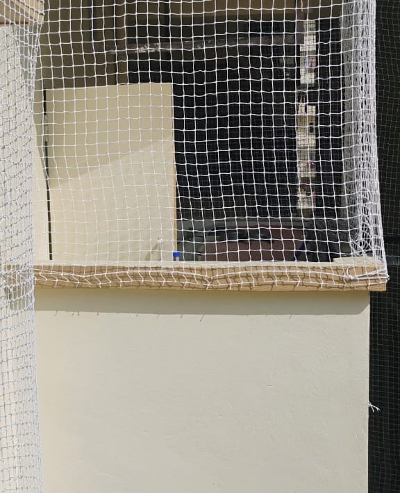 Worker carefully installing a balcony safety net on a high-rise building in Nungabakkam.