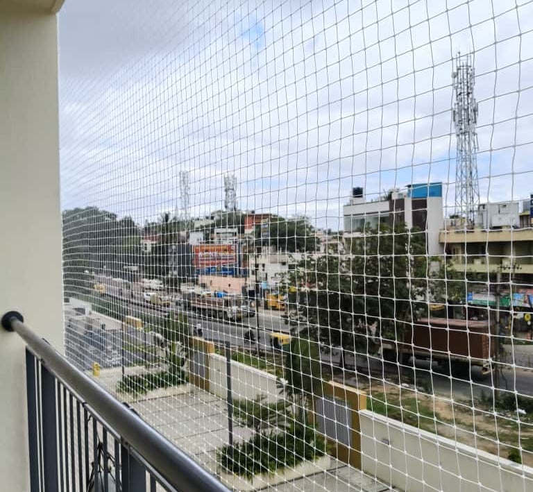 Technician carefully fitting a pigeon net frame on a window ledge in Chennai.