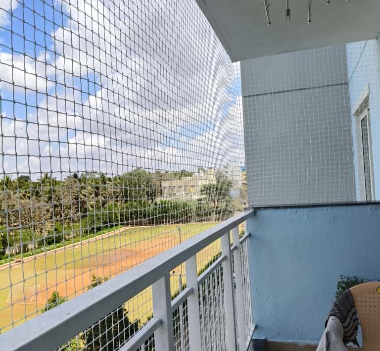 Technician carefully fixing the netting on a balcony railing in Perungudi.