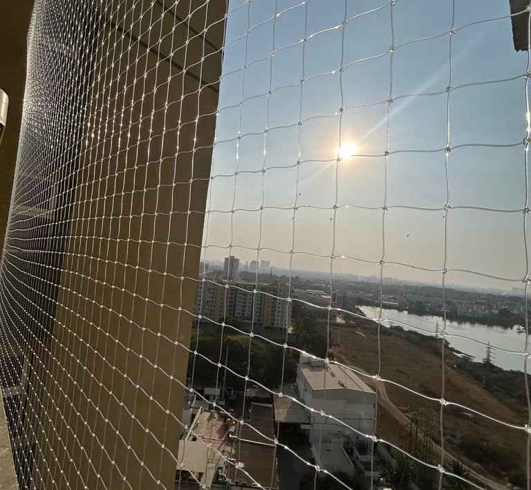 Evening view of a balcony with safety net installed, softly lit by warm indoor lights.