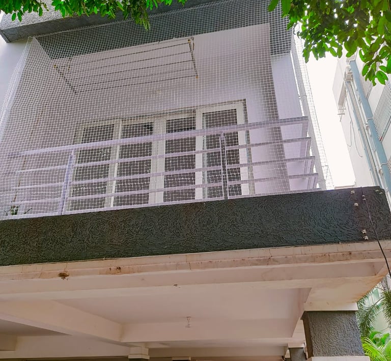 Technician carefully fitting the edges of a pigeon safety net on a residential balcony.