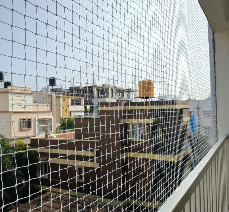 Technician from Arjilli Enterprises carefully measuring and fitting a safety net on a balcony.