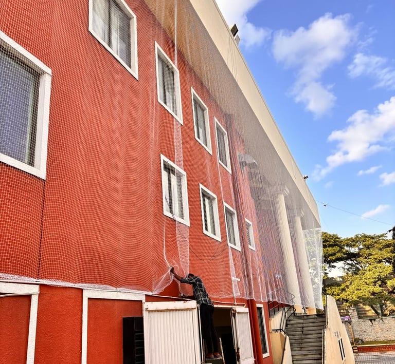 Wide shot of a high-rise balcony fully covered with durable pigeon netting against a blue sky.