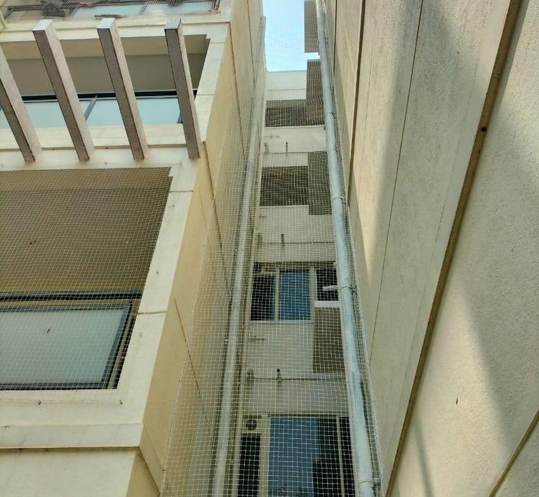 Wide shot showing a balcony fully covered with a safety net overlooking Perungudi neighborhood.