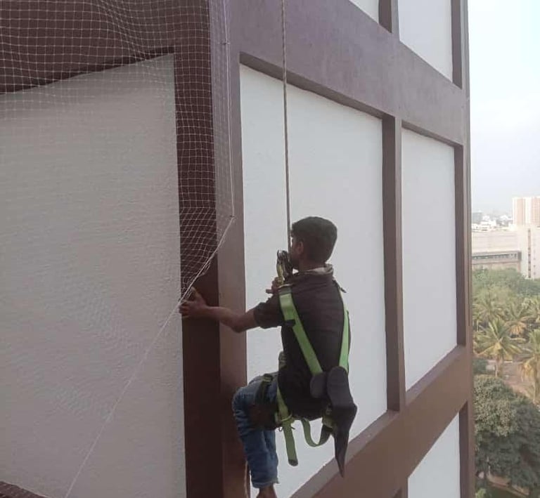 Side view of workers from Arjilli Enterprises carefully fitting pigeon nets around the gosala struct