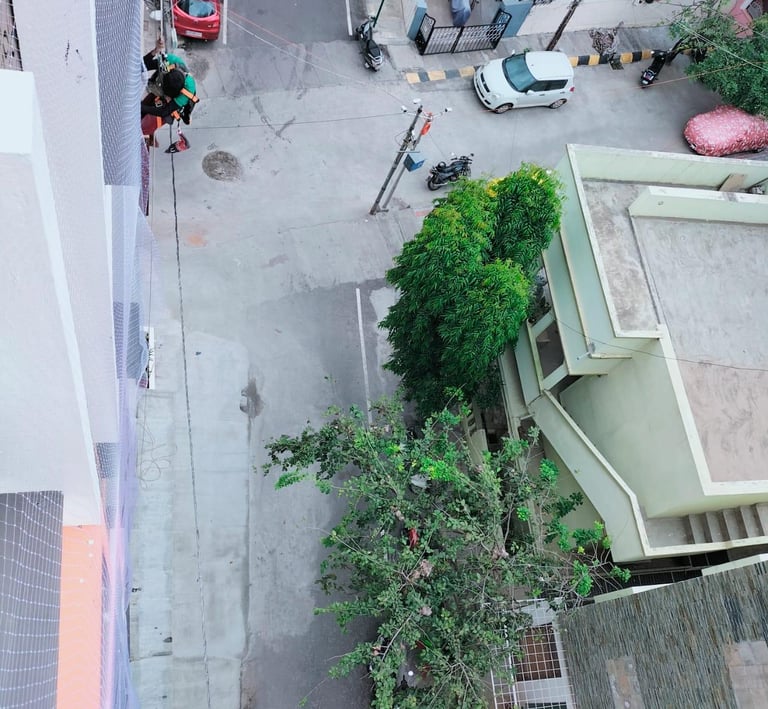 Wide shot of a high-rise apartment balcony fully covered with a protective net in Sholinganallur.