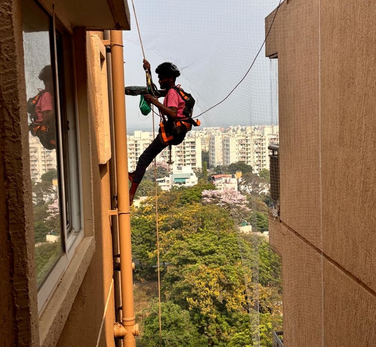 Technician from Arjilli Enterprises carefully fitting the safety net frame on a balcony.